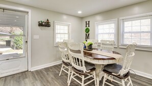 A dining room with a round table, white chairs, and a 'HOME' sign on the wall. - Secluded Getaway on 40 Acres in Lawrenceburg! (Lawrenceburg)