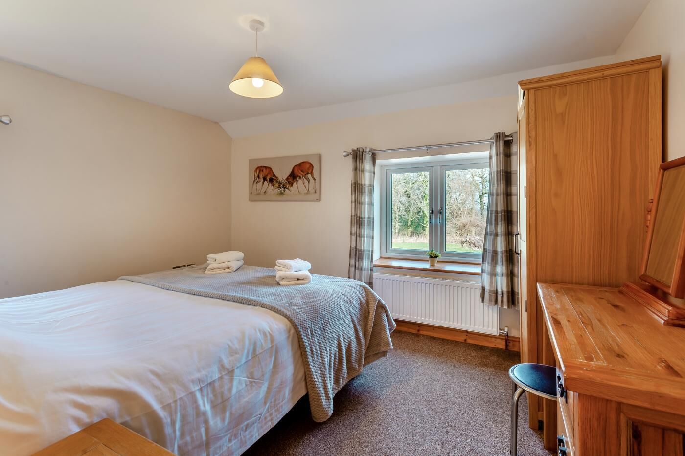 Een slaapkamer met twee bedden, een houten bureau, een radiator en een raam met gordijnen.