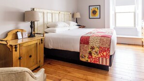 A bedroom with a wooden bed, two bedside lamps, a wooden nightstand, a chair, and a window with a view. - Strathmere Country Retreat (Ottawa)