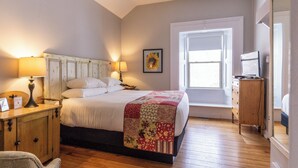 A bedroom with a bed, bedside lamps, a wooden dresser, a ceiling fan, and a window. - Strathmere Country Retreat (Ottawa)