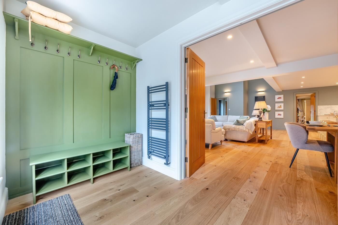 Een kamer met een groene opbergkast, een zithoek met een bank en stoelen, en een houten eettafel.