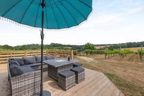 Eine Terrasse im Freien mit großem Sonnenschirm, einer Couch, einem Tisch und einem Weinglas.