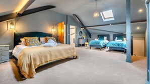 Ein geräumiges Schlafzimmer mit einem großen Bett, einem kleineren Bett und einem Schreibtisch.
