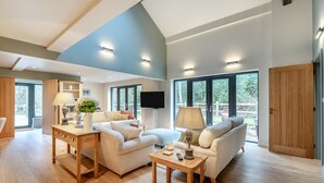 Ein geräumiges Wohnzimmer mit hohen Decken, großen Fenstern und Holzboden.
