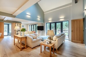 Ein geräumiges Wohnzimmer mit hohen Decken, großen Fenstern und Holzboden.