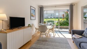 Ein modernes Wohnzimmer mit Fernseher, Esstisch und Sofa.