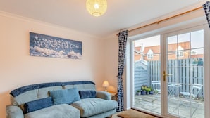 A living room with a sofa, a painting, a lamp, and a view of the outside. - 2 Bed in Snettisham (oc-d31668) (Snettisham)