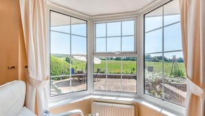 A corner room with a large bay window overlooking a garden and a lawn. - 2 Bed in Seaford (oc-l31115) (Seaford)