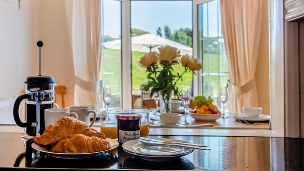 A breakfast table with croissants, coffee, juice, and a fruit bowl. - 2 Bed in Seaford (oc-l31115) (Seaford)