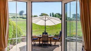 A conservatory with a table and chairs under a large umbrella, overlooking a green landscape. - 2 Bed in Seaford (oc-l31115) (Seaford)