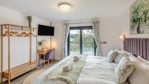 A bedroom with a bed, a desk, a chair, a TV, and a balcony with a view. - 4 Bed in Berriew (oc-t31114) (Berriew)