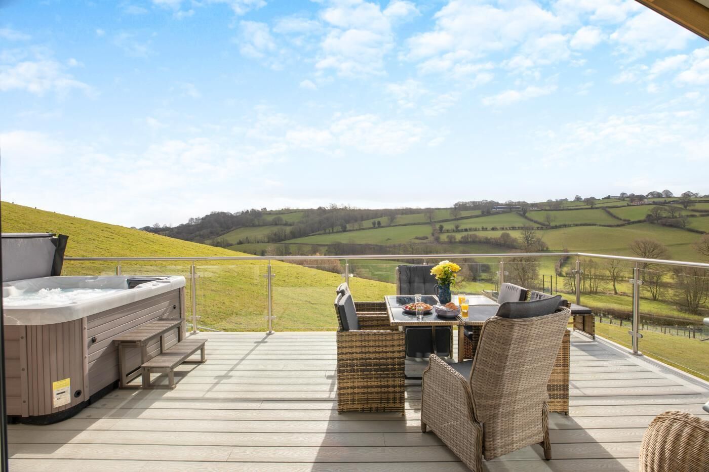 A deck with outdoor seating, a hot tub, and a scenic view of rolling hills.