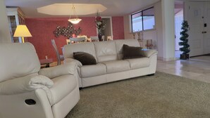 A living room with a beige sofa, a small table, a lamp, and a decorative mirror. - Desert Oasis backing Golden Hills Golf Course. (Mesa)