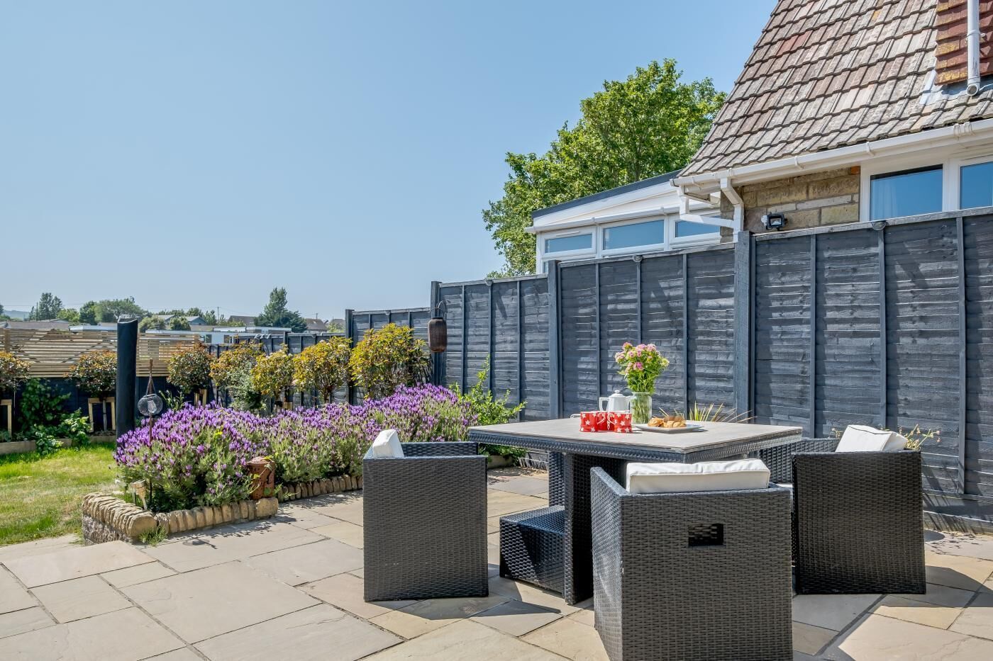 A patio with outdoor furniture, a table, and a variety of plants.