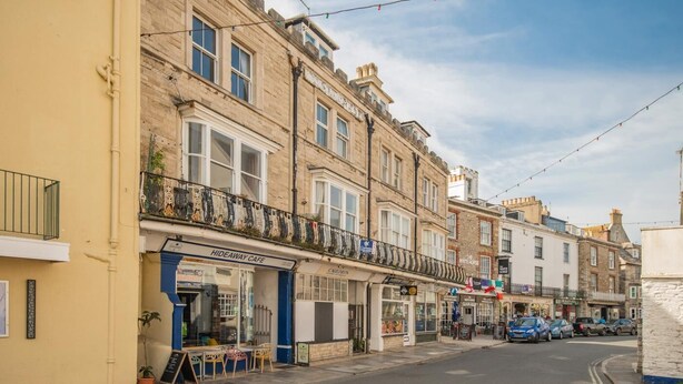 A street with buildings, including a cafe named 'Hideaway Cafe' and a shop called 'The White Horse'. - 2 Bed in Swanage (oc-b31105) (Swanage)