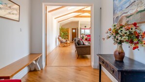 A spacious hallway with wooden flooring, a bench, a sofa, and a dining area in the background. - 3 Bed in South Cove (oc-r30975) (South Cove)