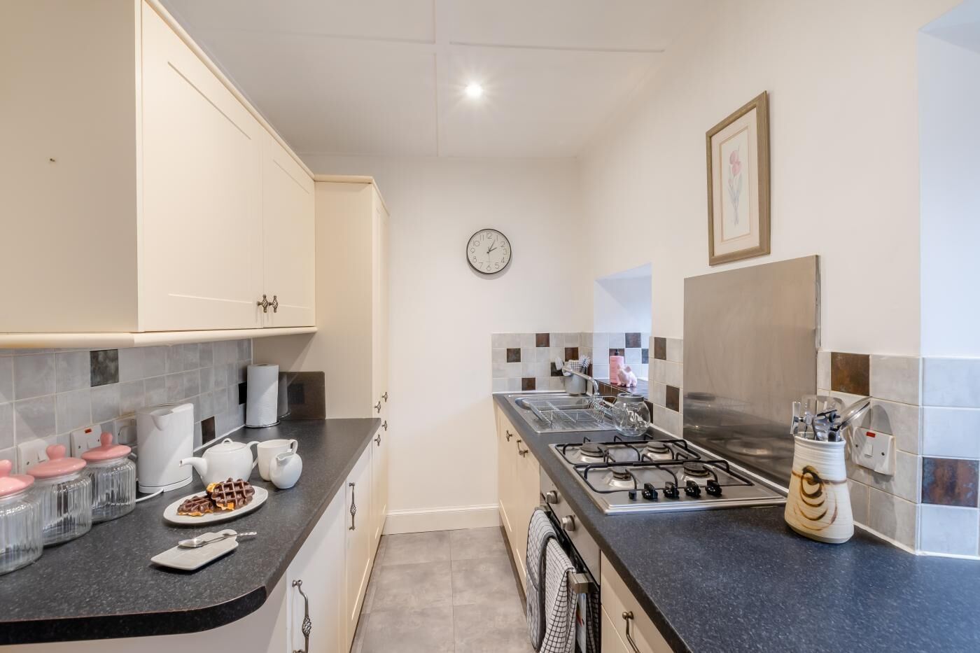 A modern kitchen with white cabinets, a gas stove, and a clock on the wall.