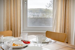 A dining table set for two with plates, glasses, and a bowl of cherry tomatoes. - 2 Bed in Hawick (oc-p30967) (Hawick)