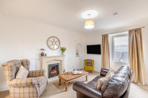 A living room with a fireplace, a sofa, a coffee table, and a television. - 2 Bed in Hawick (oc-p30967) (Hawick)