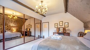 Um quarto com uma cama grande, um candelabro, uma cômoda e um espelho.
