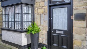 Um edifício com porta preta e janelas com cortinas de renda.