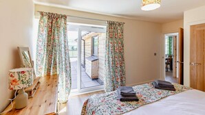 A bedroom with a bed, curtains, a bedside lamp, and a view of an outdoor area. - 2 Bed in Llanarmon Dyffryn Ceiriog (oc-b31110) (Llanarmon Dyffryn Ceiriog)