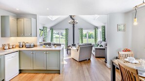 A modern kitchen with a central island, a dining area with a wooden table, and a cozy seating area with a sofa and armchairs. - 2 Bed in Llanarmon Dyffryn Ceiriog (oc-b31110) (Llanarmon Dyffryn Ceiriog)