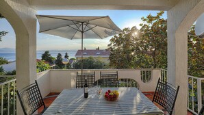 Ein Balkon mit Tisch für zwei Personen, einer Weinflasche und einer Obstschale.