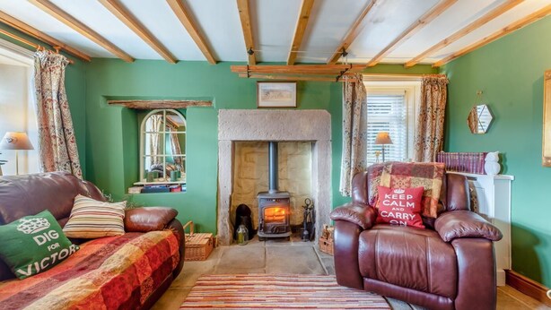A cozy living room with a stone fireplace, leather sofas, and a green wall. - 1 Bed in Starkholmes (oc-q30994) (Matlock Bath)