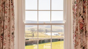 Ein Fenster mit Blick auf eine ländliche Landschaft, darunter Felder und ein Gewässer.