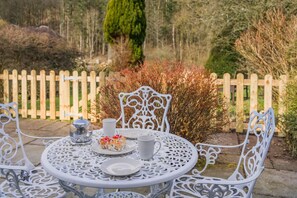 A round table with white metal chairs, a cake, a teapot, and a cup. - 2 Bed in Pooley Bridge (oc-l31060) (Pooley Bridge)
