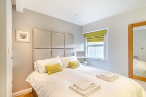 A bedroom with a large bed, a headboard, a bedside table, a window with a curtain, and a mirror on the wall. - 2 Bed in Pooley Bridge (oc-l31060) (Pooley Bridge)