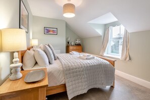 A bedroom with a bed, bedside table, lamp, and a window with curtains. - 6 Bed in Buxton (oc-s31063) (Buxton)