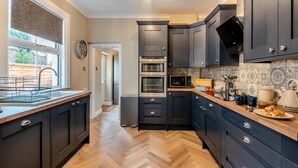 A modern kitchen with dark cabinetry, a built-in oven, microwave, and a window with a view of the outside.