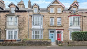 A row of terraced houses with bay windows, a red door, and a stone facade.