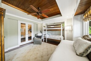Ein Schlafzimmer mit Etagenbett, einem Sessel, Deckenventilator und einem großen Fenster.