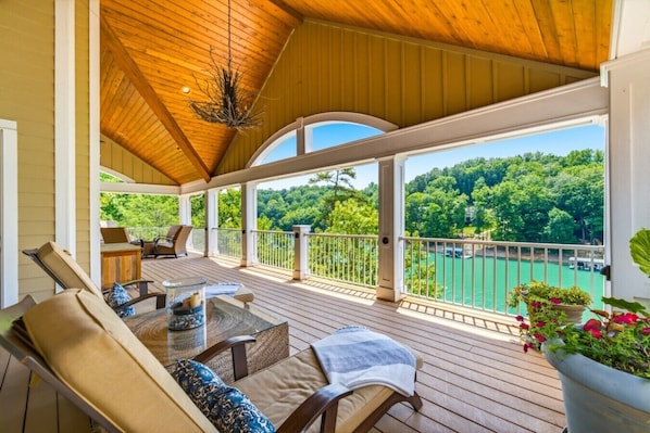 A covered outdoor deck with seating and a view of a lake. - Lux Norris Lake Home|Private Dock & Stunning Views (LaFollette)