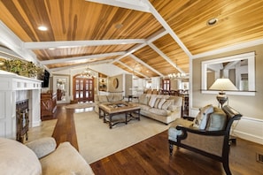 A spacious living room with a high ceiling, wooden beams, a fireplace, and a dining area. - Lux Norris Lake Home|Private Dock & Stunning Views (LaFollette)