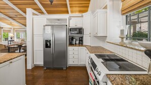Eine moderne Küche mit weißen Schränken, einem Edelstahl-Kühlschrank, einer Mikrowelle und einem Herd.