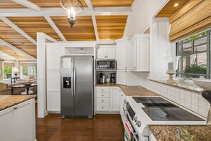 A modern kitchen with white cabinetry, a stainless steel refrigerator, a microwave, and a stove. - Lux Norris Lake Home|Private Dock & Stunning Views (LaFollette)