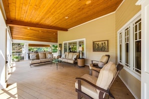 A covered porch with wooden flooring, a sofa set, a coffee table, and a chair. - Lux Norris Lake Home|Private Dock & Stunning Views (LaFollette)