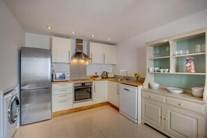 A modern kitchen with stainless steel appliances, white cabinetry, and a wooden countertop. - 2 Bed in Torquay (oc-wellme) (Torquay)