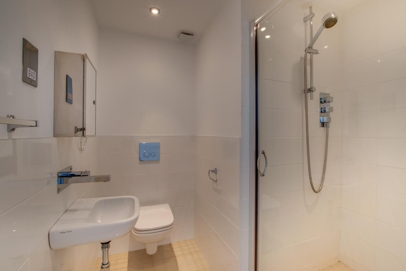A modern bathroom with a glass-enclosed shower, a white sink, and a toilet.