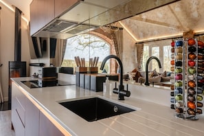 Een moderne keuken met een groot eiland, een zwarte kraan en een wijnrek.