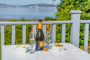 Ein Tisch mit einer Cantina Prosecco Flasche, zwei Gläsern, einer Schüssel Chips und einer Schüssel Oliven, sowie einem Korken.