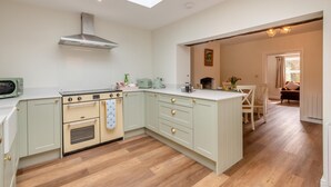 A kitchen with a skylight, a stove, and a dining area with a table and chairs. - 2 Bed in Aylsham (oc-s30931) (Aylsham)