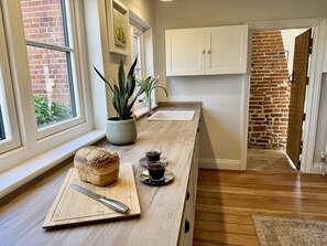 A kitchen with a wooden countertop, a loaf of bread, a knife, and a cup of coffee. - 5 Bed in Postwick (oc-w30947) (Postwick)