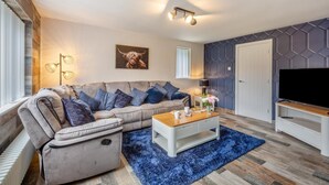 A modern living room with a sectional sofa, a coffee table, and a flat-screen TV.
