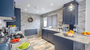 A modern kitchen with dark cabinets, a central island, and a variety of appliances.