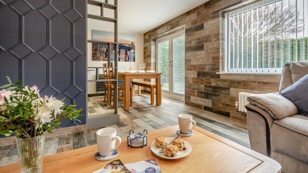 A modern living room with a wooden coffee table, a sofa, and a dining area with a table and chairs.